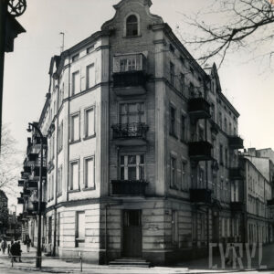 narożna, kilkukondygnacyjna kamienica z balkonami, ozdobnymi szczytami i dekoracją architektoniczną na elewacji