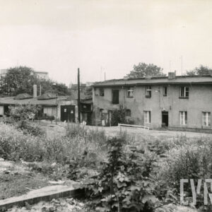 na pierwszym planie nieużytki, w głębi z prawej dwukondygnacyjny budynek, przy nim z lewej parterowa hala