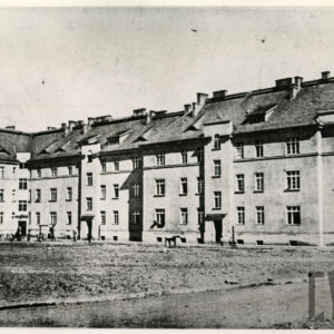 duże podwórze otoczone pięciokondygnacyjnym budynkiem mieszkalnym ze spadzistym dachem, kominami i oknami typu wole oko na strychu