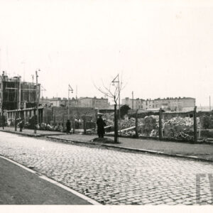 na pierwszym planie brukowana ulica, w głębi blok mieszkalny w trakcie budowy