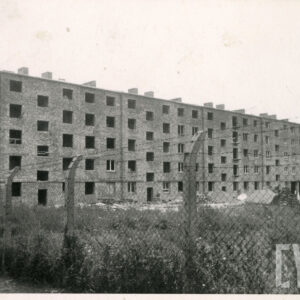 w głębi czteropiętrowy blok mieszkalny w trakcie budowy, stan surowy, teren budowy ogrodzony metalową siatką, na górze ogrodzenia drut kolczasty