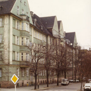 skrzyżowanie ulicy, wzdłuż ulicy kilkukondygnacyjne domy mieszkalne z trójkątnymi szczytami i spadzistymi dachami, przy ulicy drzewa