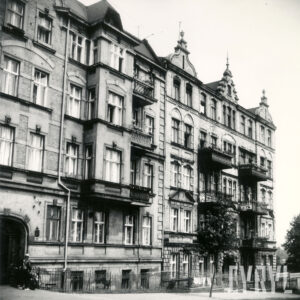 kilkukondygnacyjne połączone dwie kamienice, kamienica z lewej z przyziemiem, kamienica z prawej z ozdobnymi balkonami, przed kamienicami ogrodzone metalowym płotem przedogródki