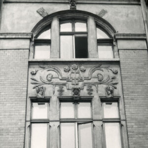 fragment elewacji z oknami dwóch kondygnacji, pomiędzy nimi dekoracja rzeźbiarska, okno wyższej kondygnacji półokrągłe