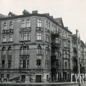 kilkukondygnacyjna kamienica narożna z balkonami i bogatą dekoracją architektoniczną