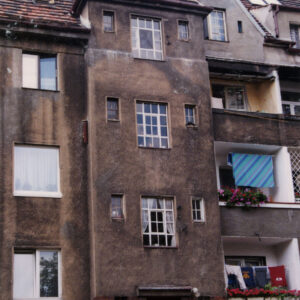 kilkukondygnacyjny budynek mieszkalny z balkonami, ryzalitem i spadzistym dachem