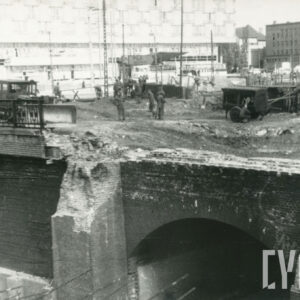 robotnicy w czasie prac rozbiórkowych ceglanych fortyfikacji, w głębi fragment nowego hotelu