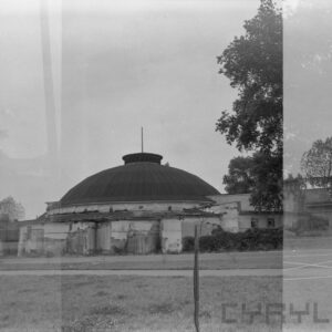 zniszczony budynek otoczony płotem i krzakami