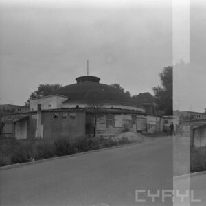 zniszczony budynek z rozległą kopułą; widoczna ulica z samochodem i przechodniem w głębi widoczne budynki mieszkalne