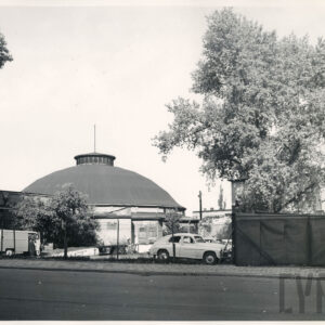 budynek z rozległą kopułą; obok niego stoją zaparkowane samochody, z boku rosną drzewa