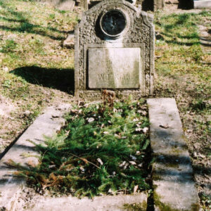 Nagrobek otoczony niskim, szerokim murkiem wyłożony gałązkami świerku. Pionowa prostokątna stela o porowatej fakturze. Tablica epitafijna z napisami, nad nią ślad po medalionie. W głębi inne nagrobki.