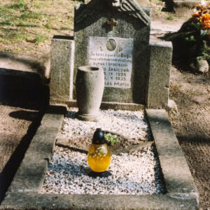 Nagrobek otoczony murkiem z białymi kamyczkami, zniczem i kamiennym wazonem wewnątrz. Prostokątna stela z uskrzydloną głową anioła i dwoma wysuniętymi słupkami. Biała tablica epitafijna ze śladem po medalionie.