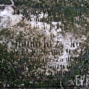 Silnie zabrudzona i omszona prostokątna tablica z  napisami. Miejscami przebija biały marmur.