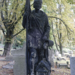 Duża figura świętego Floriana. Za nią inne nagrobki i drzewa.