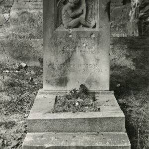 Obmurowany nagrobek ze stopniem i pionową, prostokątną stelą. Stela z płaskorzeźbą nagiego chłopca grającego na harfie, krzyżem greckim i napisami.