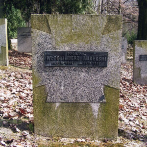 prostokątna płyta nagrobna z tablicą epitafijną pośrodku, w tle widoczne inne nagrobki