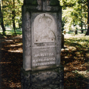 pionowa prostokątna płyta nagrobna stojąca na cokole, z płaskorzeźbą i wyrytymi napisami w języku polskim