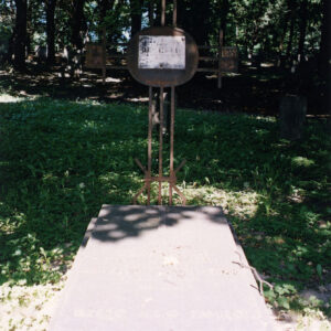 pozioma prostokątna płyta nagrobna z umiejscowionym na wieku pionowym krzyżem z żelaza, na którym zamontowano tablicę epitafijną