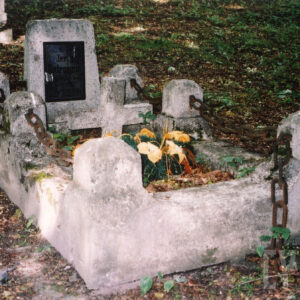 Obmurowana szerokim murkiem mogiła ze słupkami połączonymi pokrytymi rdzą łańcuchami. Stela z czarną tablicą z inskrypcją. Wokół teren zielony.