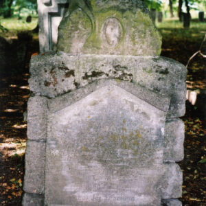 Zniszczony nagrobek z nieczytelną tablicą epitafijną i śladem po medalionie portretowym.