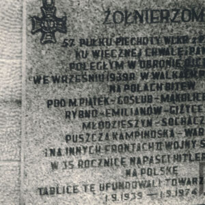 tablica z napisami w języku polskim zamontowana na betonowym sześcianie