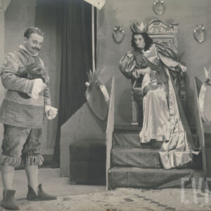 na tronie siedzi kobieta w długiej sukni i koronie, obie dłonie zaciska w pięści, obok stoi mężczyzna z wąsami, w prawej ręce trzyma nakrycie głowy