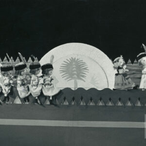 Krakowianka i Krakowiak stoją obok siebie z prawej strony sceny, po lewej stronie siedzą jedna za drugą lalki w strojach krakowiaków