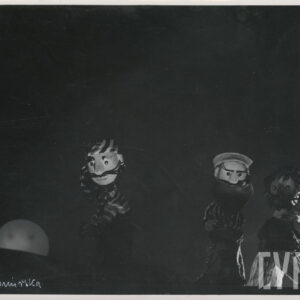 na scenie znajdują się trzy lalki, dwie z nich są ubrane w koszule w paski i nakrycia głowy, trzecia jest ubrana w spodnie w paski i szal, wszystkie postacie mają długie wąsy