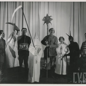 scena zbiorowa, przed opuszczoną kurtyną stoi obok siebie ośmiu aktorów, wśród nich są osoby przebrane za anioła, diabła, turonia i śmierć z kosą w rękach