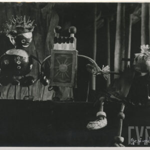 na scenie obok siebie stoją dwie kukiełki - ludzik z kasztanów i postać w kształcie częściowo otwartego pudełka zapałek, obok przysiadła kolejna lalka z długim nosem i ubrankiem w kształcie liści