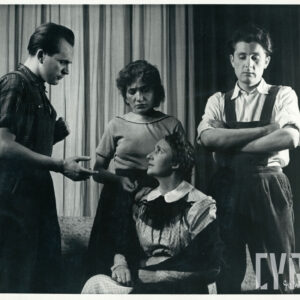 na scenie znajduje się czworo aktorów, dwie kobiety i dwaj mężczyźni, jedna z kobiet siedzi, pozostałe osoby stoją za nią w różnych pozach