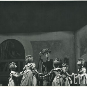 lalki w długich sukniach stoją w kręgu chwytając się za ręce, w środku lalka przedstawiająca diabła