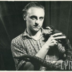 mężczyzna w koszuli w kratę trzyma w rękach kukiełkę przedstawiającą węża