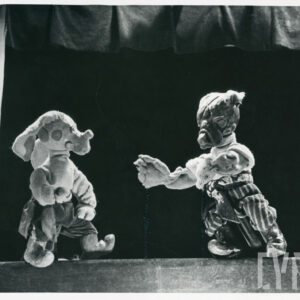 na scenie naprzeciw siebie stoją dwie lalki - wilk i pies, obie ubrane w spodnie i swetry
