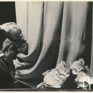 na scenie opuszczona kotara i trzy lalki - dwie świnki skulone przed kotarą i spoglądający na nie zza kotary wilk