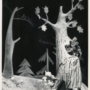 scenografia przedstawia las, na scenie znajdują się dwie kukiełki - wiewiórka w dziupli na drzewie i kot pod drzewem