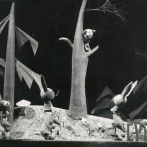 scenografia przedstawia las, na scenie znajdują się cztery kukiełki - na drzewie siedzi kot, pod drzewem trzy zające