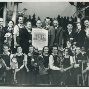 grupowe zdjęcie, w pierwszym rzędzie na stopniu siedzą obok siebie kobiety i mężczyźni z kukiełkami w rękach, ludzie w drugim rzędzie stoją, dwie osoby pośrodku trzymają plakat 