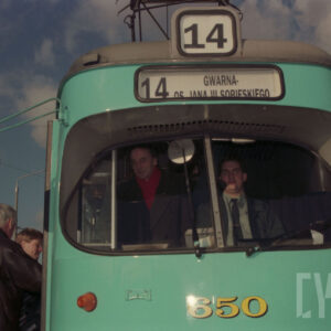 dwóch mężczyzn siedzących w kabinie motorniczego tramwaju 