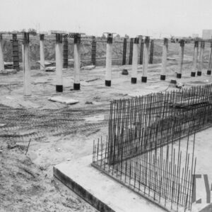 filary stojące na piaszczystym terenie; obok widoczne fundamenty z szalunkiem i hałdy piasku