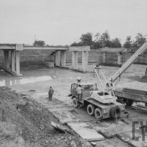 filary stojące na piaszczystym terenie; obok widoczne maszyny budowlane