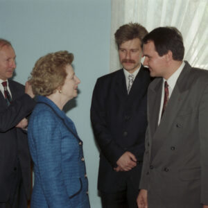 elegancka, starsza kobieta rozmawiająca z dwójką mężczyzn w średnim wieku, ubranych w garnitury