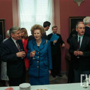 grupa starszych, elegancko ubranych osób z kieliszkami wina w dłoniach