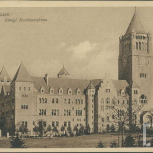 jedna z elewacji potężnego zamku z wysoką wieżą zegarową i rzędami okien, na pierwszym planie fragment parku z rozległym trawnikiem