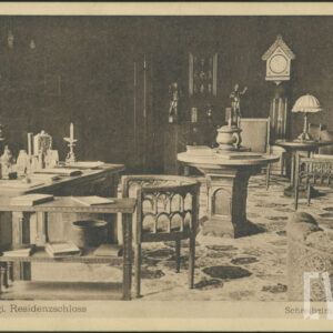 ciemny pokój wyposażony w bogato zdobione, drewniane meble: biurko, sześciokątny i owalny stół, krzesła z podłokietnikami, sofę, na ścianie wiszą zegar i obraz, na biurku i stolikach stoją lampy z abażurami