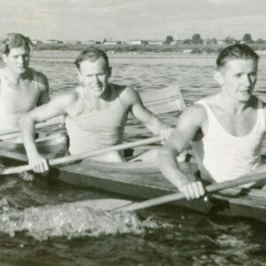 czterech młodych, dobrze zbudowanych mężczyzn płynących w kajaku, każdy z nich trzyma wiosło