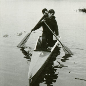 młodzi mężczyźni w dresach, wiosłujący w kajaku