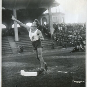 młody mężczyzna pchający kulą na rzutni sportowej na stadionie, w tle trybuny