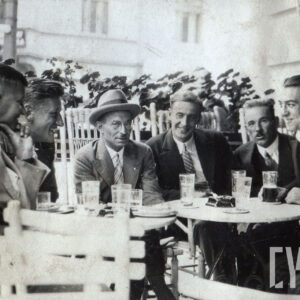 grupa mężczyzn siedzących przy stolikach w kawiarni