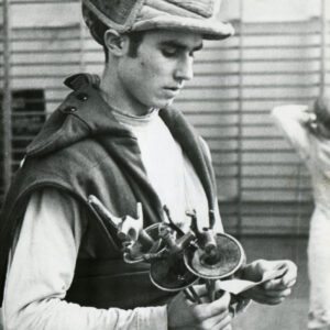 mężczyzna w stroju szermierza z podniesioną maską szermierczą i floretami w dłoni